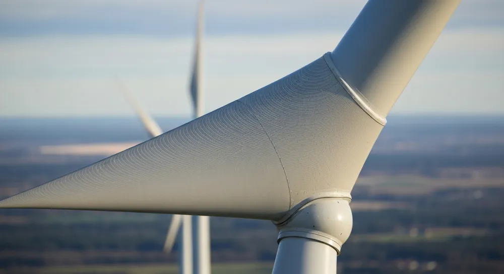 Turbinas eólicas frente a una vibrante puesta de sol con campos verdes.
